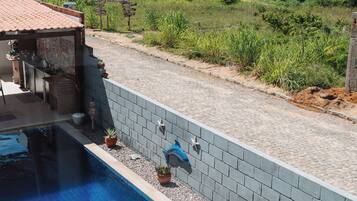 A swimming pool with a tiled deck, a brick wall, and a view of the ocean.