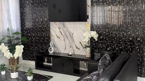Ein modernes Wohnzimmer mit einer schwarzen Ledersofa, einem schwarzen Couchtisch und einer schwarzen Unterhaltungsanlage mit Flachbildfernseher.