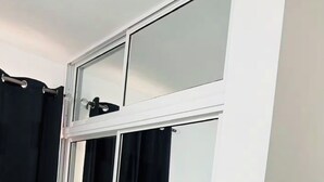 Ein Badezimmer mit weißen Fliesen, einem schwarzen Duschvorhang und einer spiegelnden Schiebetür.