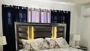 Una camera da letto con un letto, tende, comodini e una testiera.