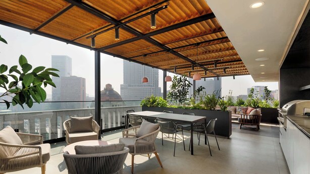 Une terrasse sur le toit, aménagée avec des meubles en osier, une table à manger et un coin cuisine.