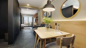 Une chambre d’hôtel moderne avec un coin repas, un grand miroir, une plante en pot et une vue sur la ville.