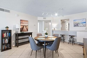 A modern dining area with a round table, chairs, a bookshelf, and artwork on the walls.