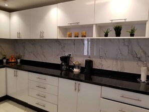 A modern kitchen with white cabinets, a black countertop, and a marble backsplash. - Pleasant family stay in a superb 5-bedroom villa with private pool. (Marrakech)