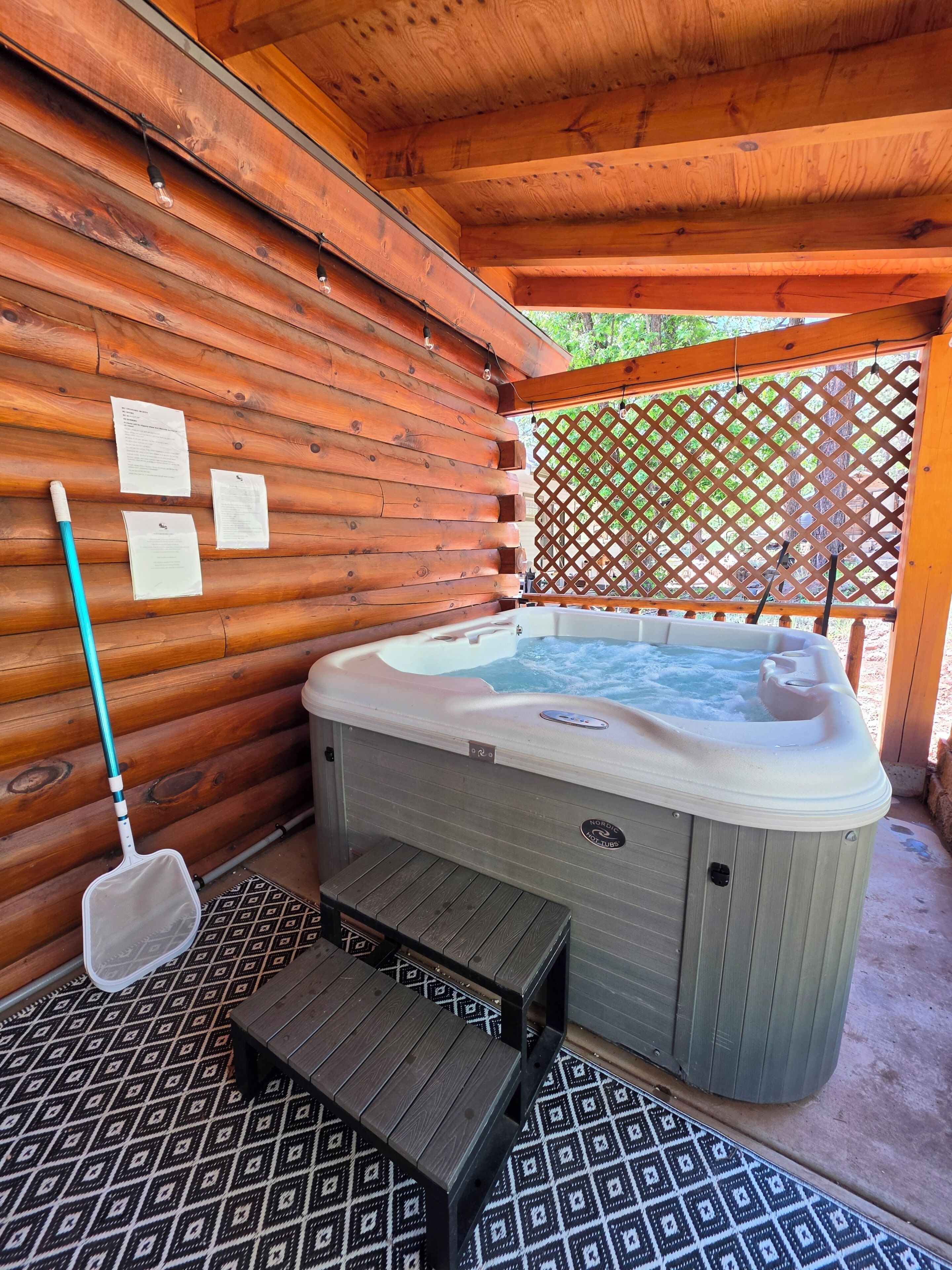 A wooden cabin with a hot tub, a wooden bench, and a paddle broom.