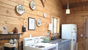 A kitchen with wooden walls, a stove, a microwave, and a refrigerator. - Cozy Log Cabin Retreat :: Hot Tub :: Forest Views (Flagstaff)