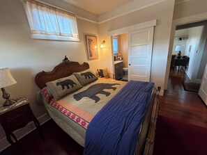 A bedroom with a bed, a nightstand, a window with curtains, a door, and a hallway leading to another room. - Historic Craftsman Bungalow Old Pasadena Rose Bowl 3 miles, LA Coliseum (Pasadena)