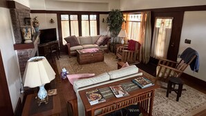 Een woonkamer met een bank, salontafel, televisie en een open haard.