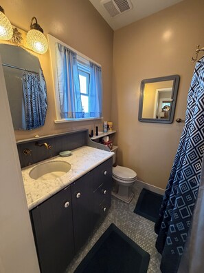 A bathroom with a marble sink, dark cabinets, a toilet, a shower curtain, and a mirror. - Historic Craftsman Bungalow Old Pasadena Rose Bowl 3 miles, LA Coliseum (Pasadena)