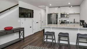 Una cucina moderna con mobili bianchi, elettrodomestici in acciaio inossidabile, un piano di lavoro in granito e un pavimento in legno.