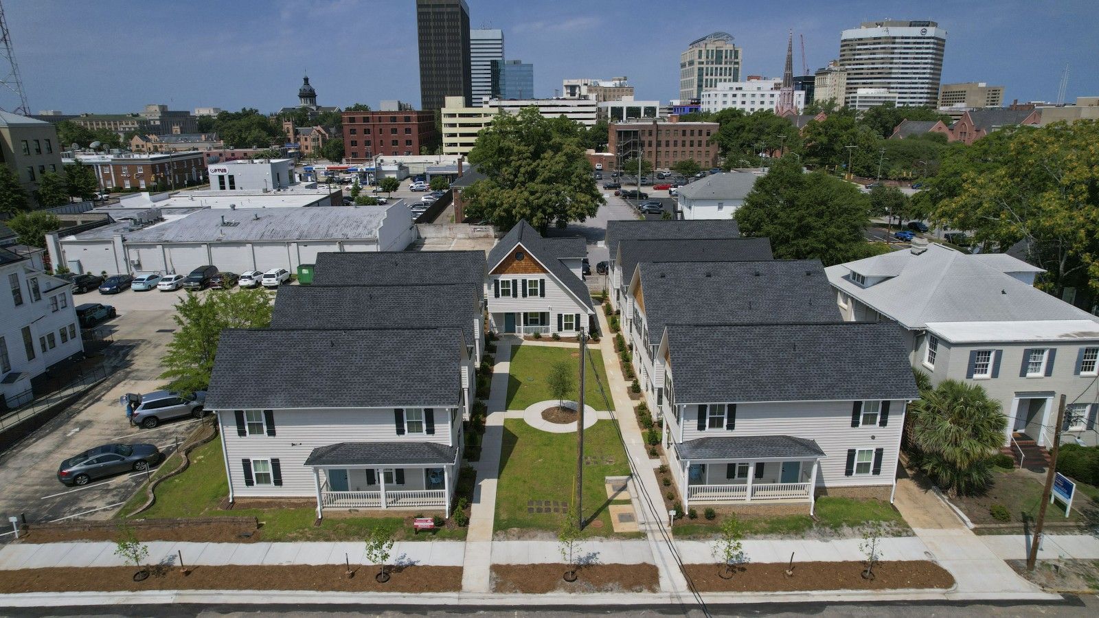 A residential area with houses, a parking lot, and a city skyline in the background.