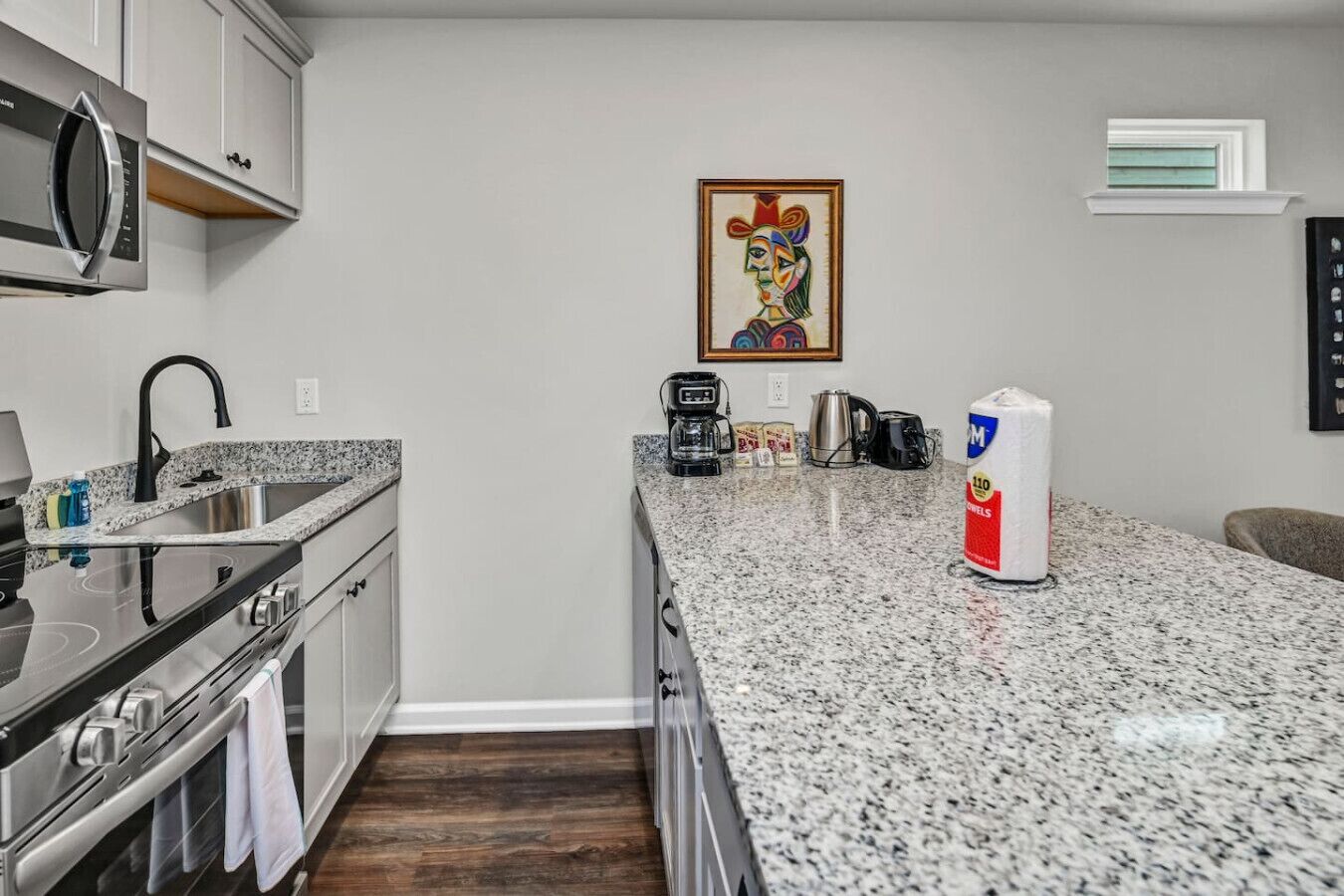 A kitchen with granite countertops, stainless steel appliances, a coffee maker, and a microwave.