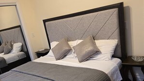A neatly made bed with a grey headboard, a grey blanket, and two pillows. - Stunning Elmwood Village Lower  (Buffalo)