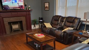A living room with a fireplace, leather sofas, a coffee table, and a television. - Stunning Elmwood Village Lower  (Buffalo)
