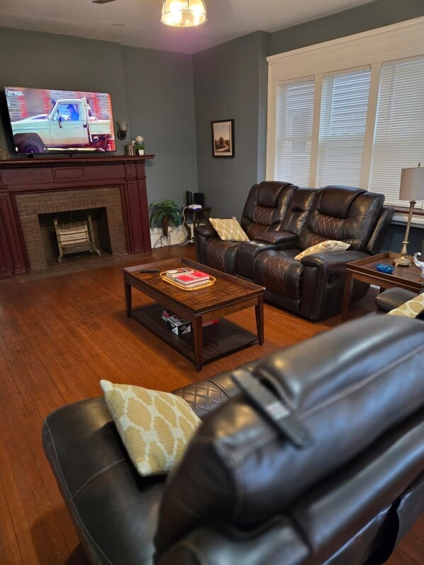 A living room with a fireplace, leather sofas, a coffee table, and a television.