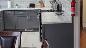 A kitchen with grey cabinets, a microwave, a gas stove, and a fire extinguisher. - Stunning Elmwood Village Lower  (Buffalo)