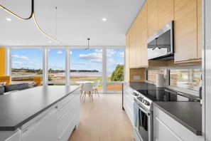 A modern kitchen with a large island, stainless steel appliances, and a view of a natural landscape.