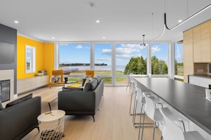 A modern kitchen with a large island, a dining area with bar stools, and a sofa.