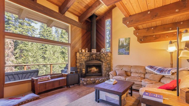 A cozy living room with a stone fireplace, wooden beams, a sofa, and a coffee table. - Monthly Lease - Pine Trail at Alpine Meadows - Pet Friendly w Hot Tub at Alpine Meadows (Alpine Meadows)