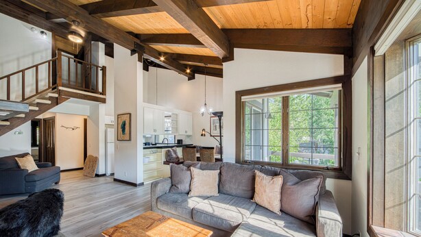 Un vaste espace de vie comprenant un grand canapé, une table basse en bois et un escalier menant à un niveau supérieur.
