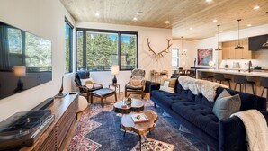 Een moderne woonkamer met een open haard, een bank, een eethoek en een keuken.