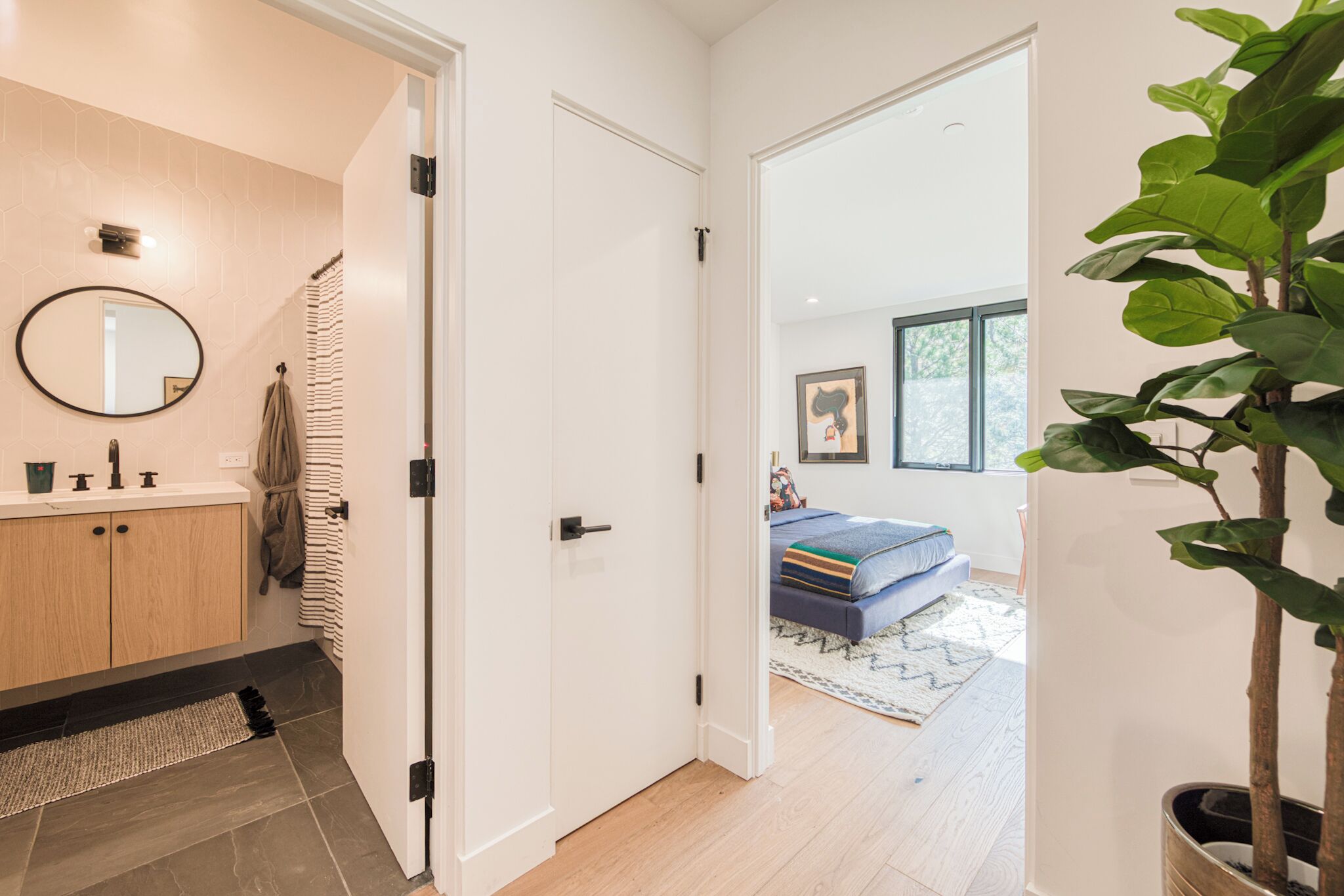 A modern bathroom with a wooden vanity, a round mirror, and a towel rack.