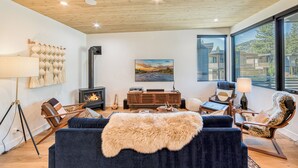 Een moderne woonkamer met een open haard, comfortabele zithoek en een groot raam met uitzicht op de omgeving.