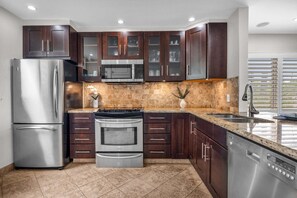 Una cocina moderna con electrodomésticos de acero inoxidable, armarios de madera oscura y encimera de granito.