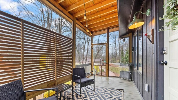 A covered outdoor seating area with a patterned rug, wooden slats, and a bench. - The Nook - Cozy Bungalow in the Countryside (Weaverville)