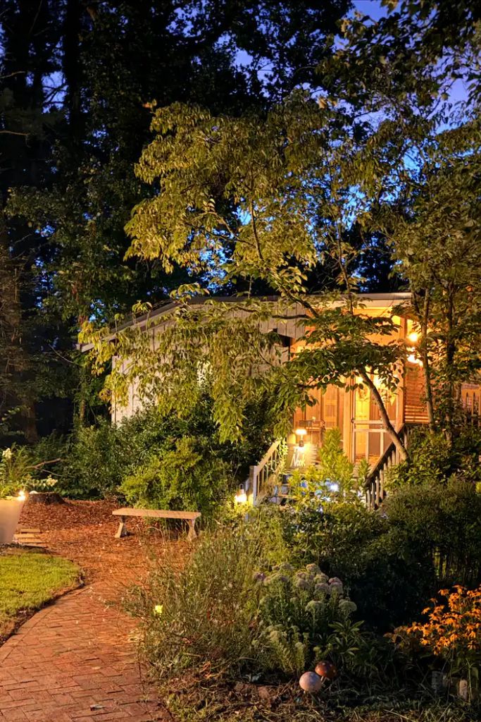 A house surrounded by dense foliage, with a pathway leading to the entrance.