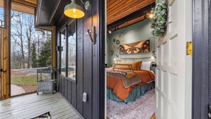 A bedroom with a bed, a window, a door, and a wall with decorative plates. - The Nook - Cozy Bungalow in the Countryside (Weaverville)