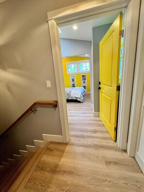 A staircase leading to a room with a bed, a window, and a door.