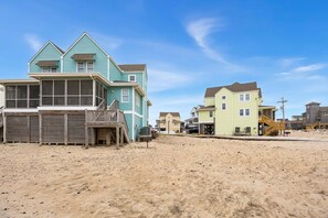 A beachfront property with a large house featuring a balcony and a smaller attached structure.