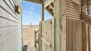 Una struttura in legno con cancello metallico, pavimento in cemento e vista libera sulla spiaggia sabbiosa.