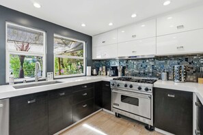 A modern kitchen with dark cabinetry, a stainless steel stove, and a tiled backsplash.