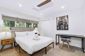 A modern bedroom with a bed, bedside tables, a desk, and a chair.
