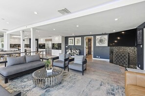 A spacious living area with a sofa, armchairs, a coffee table, and a fireplace.
