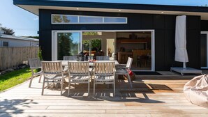Et moderne hus med terrasse, udendørs møbler og et synligt køkkenområde.