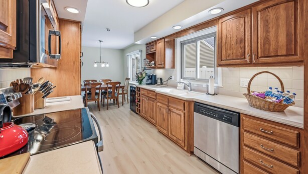 A modern kitchen with wooden cabinets, stainless steel appliances, and a dining area with a table and chairs. - Cozy fully remodeled home in Hermitage. (Hermitage)