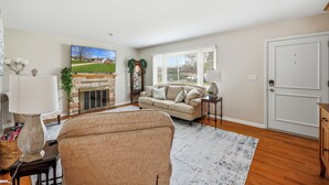A living room with a fireplace, a sofa, a television, and a door. - Cozy fully remodeled home in Hermitage. (Hermitage)