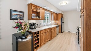 A modern kitchen with wooden cabinets, a built-in wine rack, a refrigerator, and a window. - Cozy fully remodeled home in Hermitage. (Hermitage)