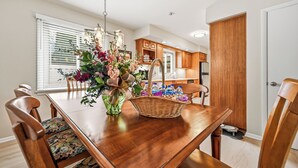 A dining table with chairs, a vase with flowers, a basket with water bottles, and wooden cabinets in the background. - Cozy fully remodeled home in Hermitage. (Hermitage)
