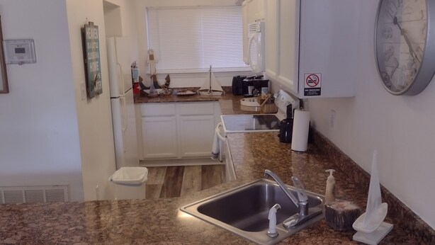 A kitchen with a granite countertop, stainless steel sink, and a clock on the wall. - Charming 2-bedroom condo with AC in Biloxi breeze (Biloxi)