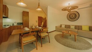 A modern living room with a sofa, a coffee table, and a dining area with wooden furniture and hanging lights. - Luxury 2 Bedroom Villa with Private Pool in Umalas (Badung)