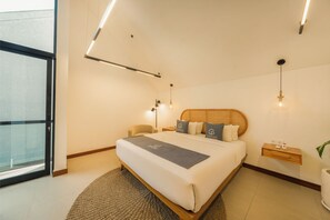 A modern hotel room with a large bed, bedside tables, a small desk, and a view through a glass door. - Luxury 2 Bedroom Villa with Private Pool in Umalas (Badung)