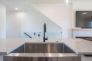 Una cocina moderna con un lavamanos de acero inoxidable, un grifo negro y una encimera.