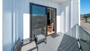 En balkon med glasdør, stol og lille bord.