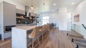 Et moderne køkken med en marmorø, barstole og et spiseområde med glasgelænder.