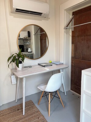 Un espace de travail compact comprenant un bureau, une chaise et un miroir rond.