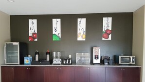 Uma cozinha compacta equipada com geladeira, cafeteira, liquidificador, torradeira, micro-ondas e dispensador de café.